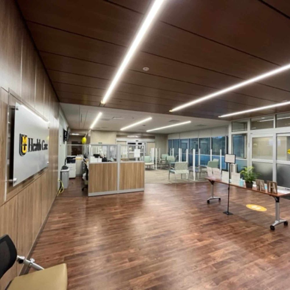 Lobby are of MU Health Care Clinic with check-in desk and waiting area modern lighting wood panels